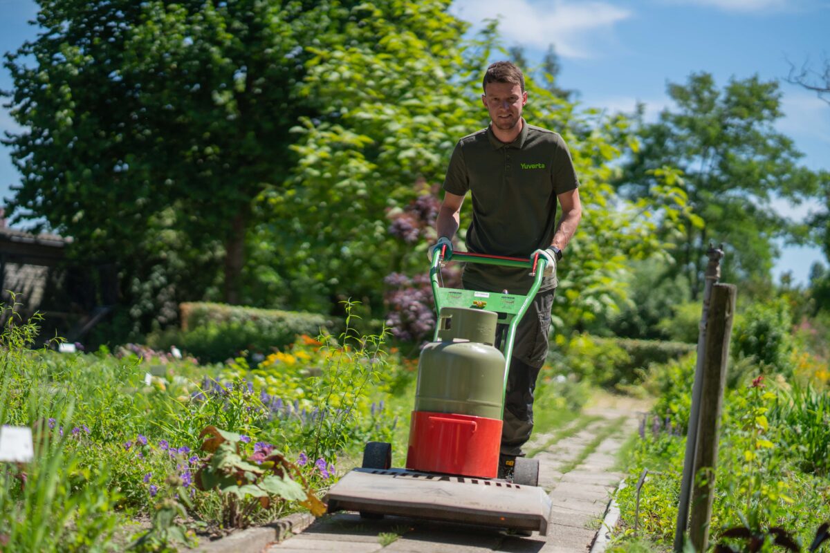 Yuverta-llo-opleidingen-hovenier Man aan het werk in een tuin met een machine - opleidingen hovenier